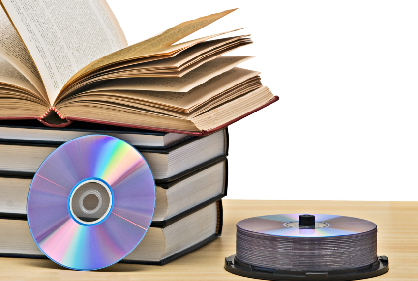 Stack of books with an opened book on top and cd's next to them.