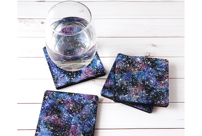 Top view of glass on galaxy themed coasters. 