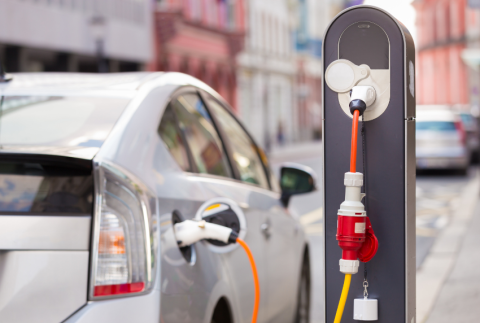 Car plugged into electric car charging station. 