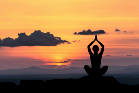 Sunrise and silhouette of person meditating.