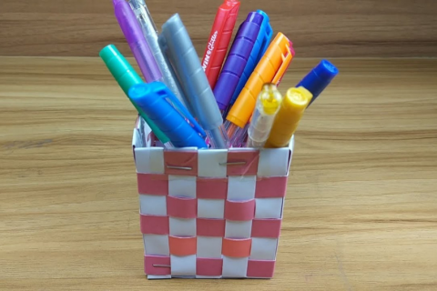 a pencil holder made of paper that is filled with markers 