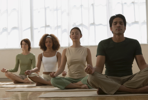 four people meditating on floor 