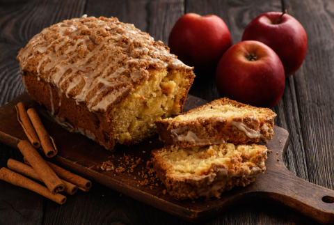 Caramel apple bread with apples and cinnamon sticks around it.