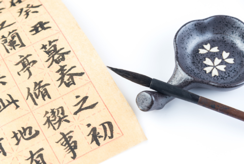 Top view of calligraphy brush, bowl and paper.