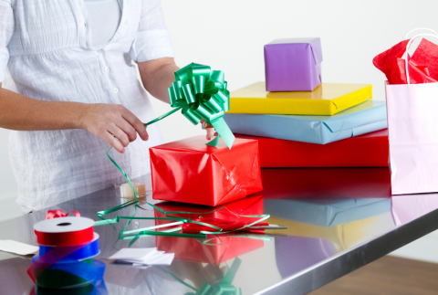 Side view of presents and hands gift wrapping.