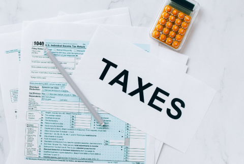 Top view of a tax form, calculator and the word taxes.