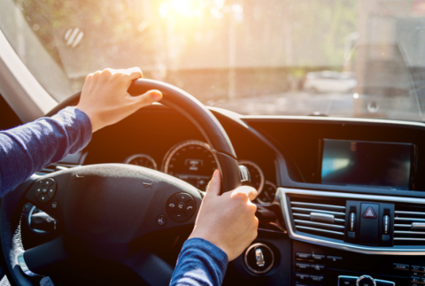 Hands on a steering wheel in a car.