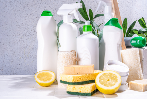 Cleaning products behind lemon and sponges. 