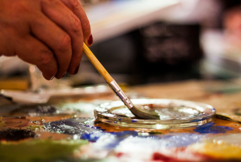 Hand holding a brush in a dish.