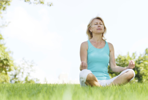 Woman sitting on grass in lotus position