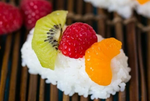 Kiwi, raspberry, and orange lined up on rice to look like sushi.