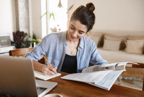 Lady sitting at table with laptop doing work. 