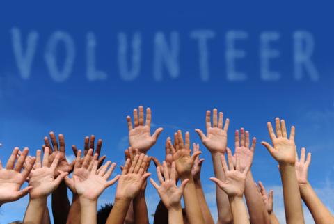 Picture of many hands held up under the word volunteer