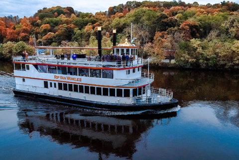 Boat on river with fall foliage in back ground. 