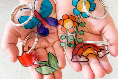 Hands holding bunch of shrinky dink key chains. 