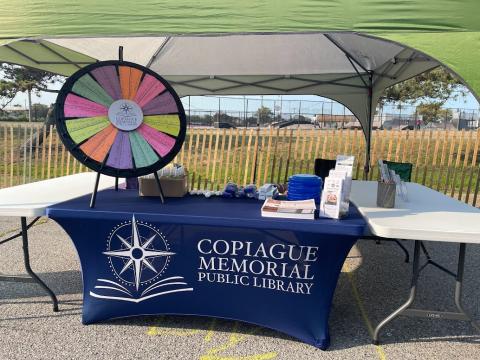 Table with blue tablecloth and prize wheel on table. 