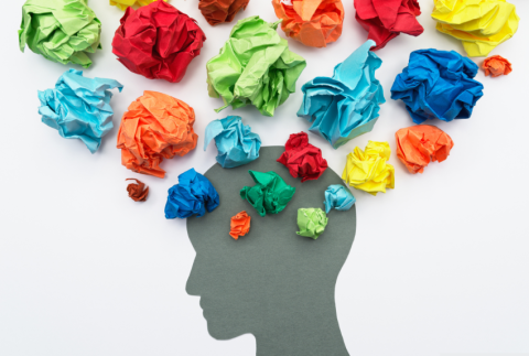 Side profile of face cut out with crumpled colored paper coming out of top. 