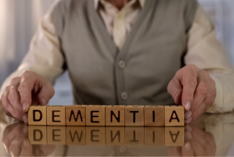 Wooden blocks that read Dementia in between persons hands.