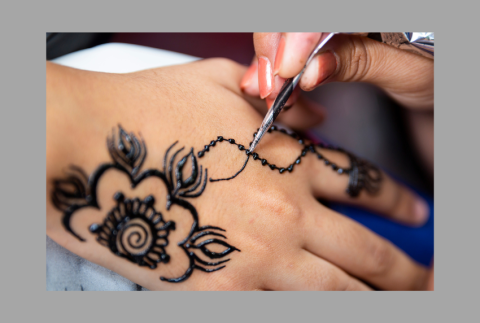 Hand decorating another hand with henna. 