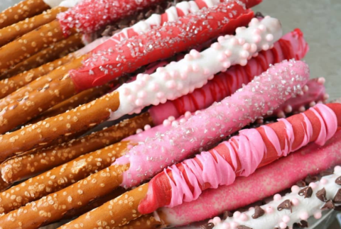 Top view of pretzels dipped in pink chocolate and sprinkles. 