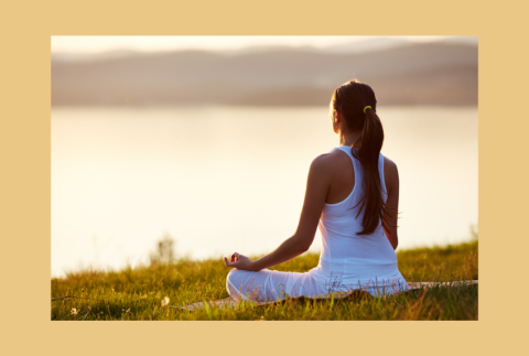 Person facing water and meditating. 