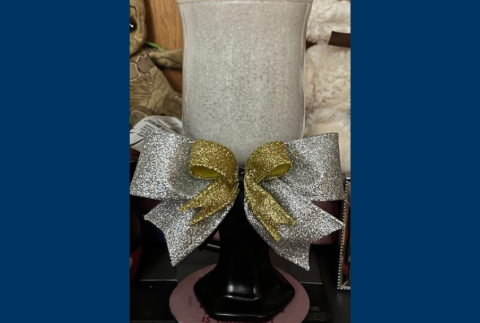 Hurricane vase with a silver and gold bow. 