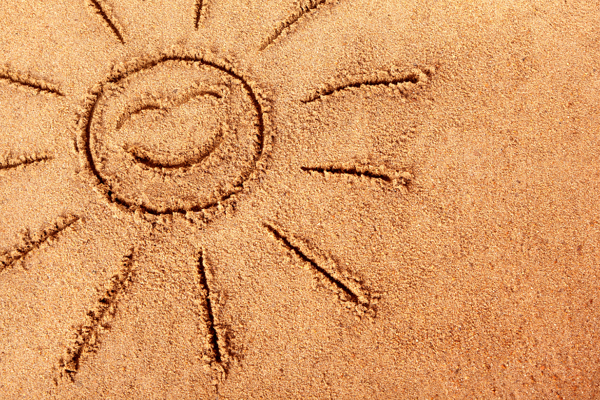 A sun with a smiley face drawn in the sand.