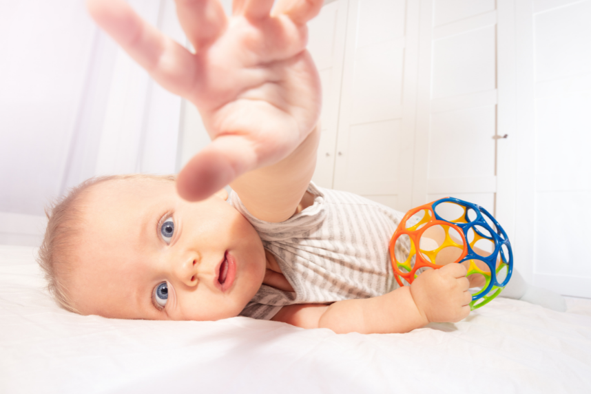 Baby stretching and holding toy