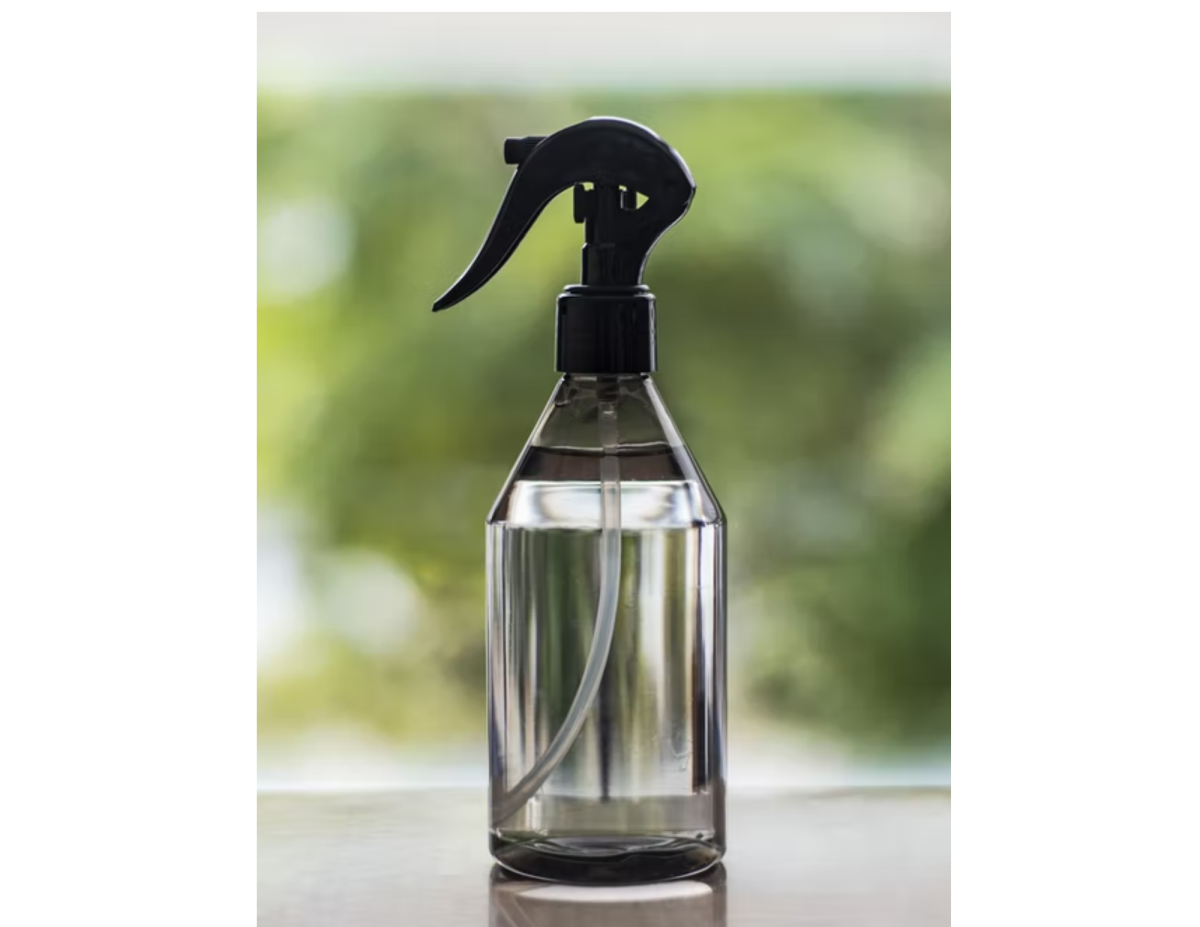 Spray bottle with plants in background