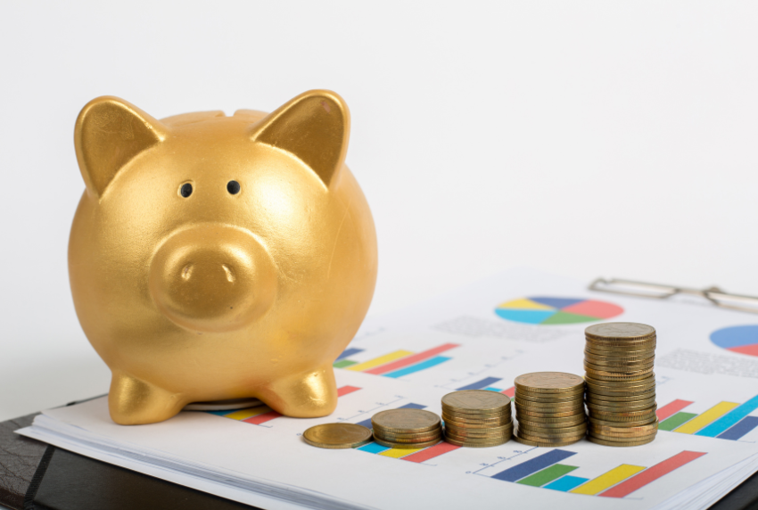 Gold pig next to a stack of coins.