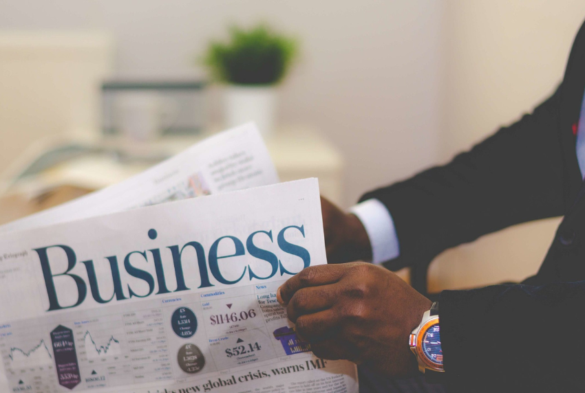 Man holding a newspaper that reads business.