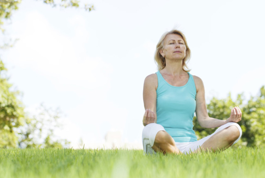 Woman in lotus pose on grass