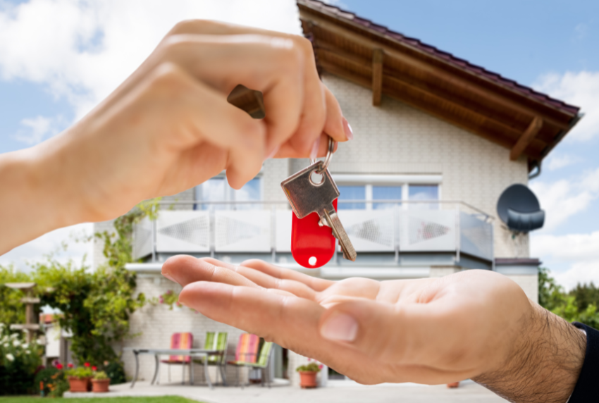 House in back with hand on top handing keys to hand on bottom. 