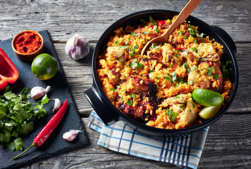 Top view of skillet with chicken and rice and cutting board with peppers.