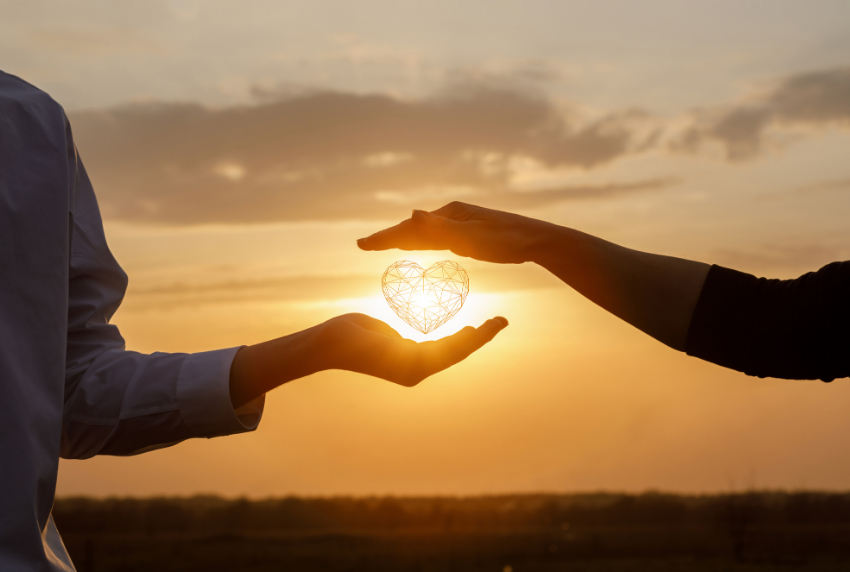 Hand on top of each other with sun in background.