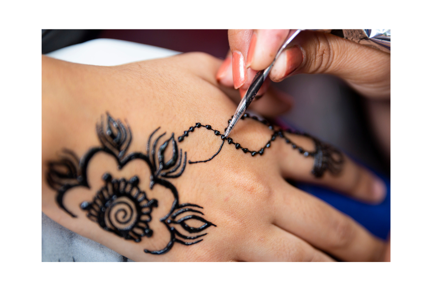 Hand with henna design being drawn on.