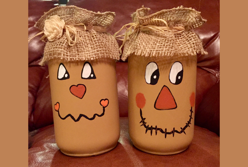 Two mason jars painted like scarecrows. 