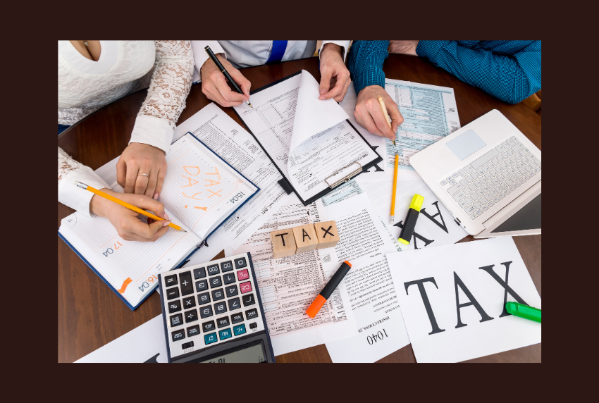 Top view of paper work, calculator and the word TAX. 