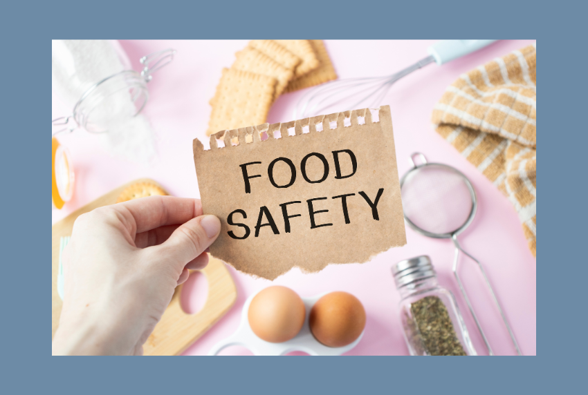 Top view of person holding sign saying food safety with food items underneath.