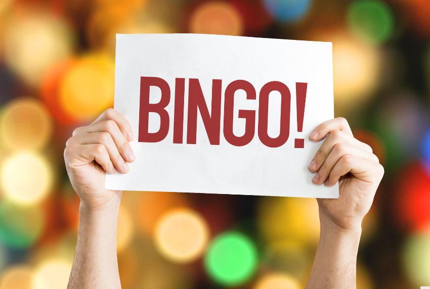 Hands up in the air holding a sign that reads BINGO.