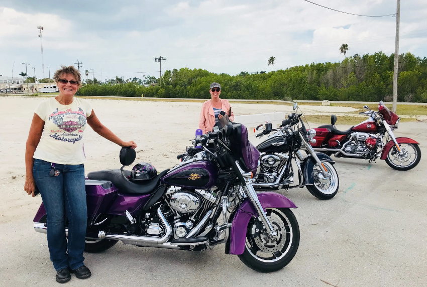 Women standing next to motorcycles. 