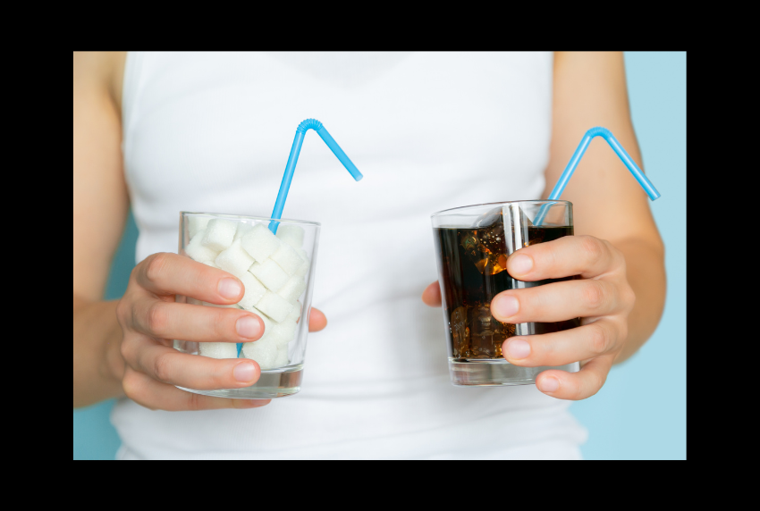 Person holding a glass of soda and a glass of sugar cubes.